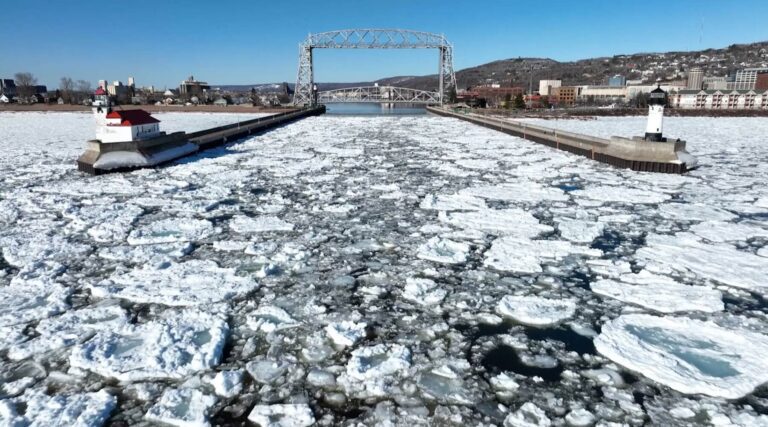 Icy landscape of a harbor with floating ice and a lighthouse in Duluth.